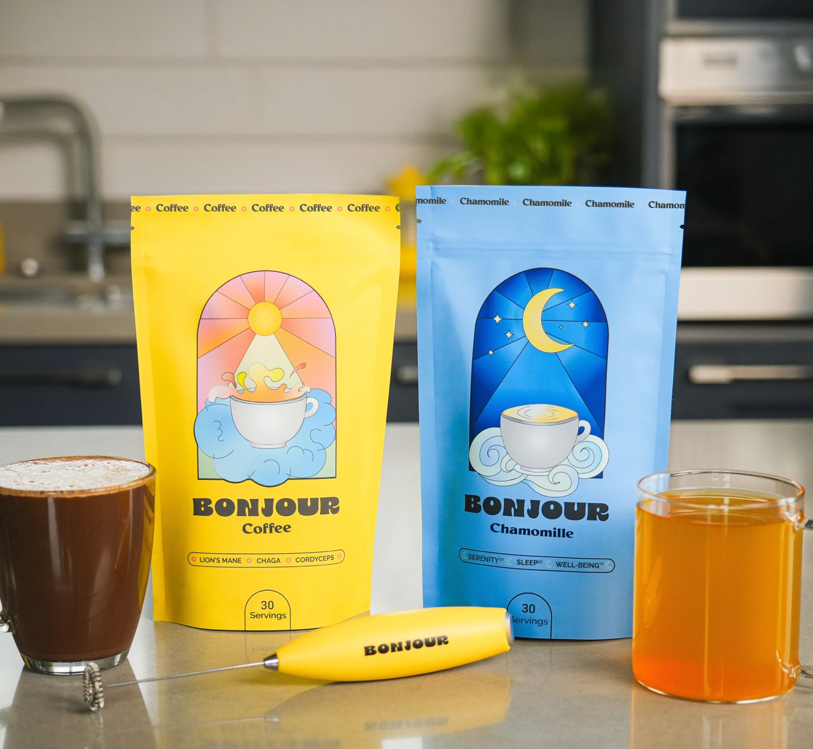 Two Bonjour pouches, a milk frother and two prepared glasses on a kitchen counter